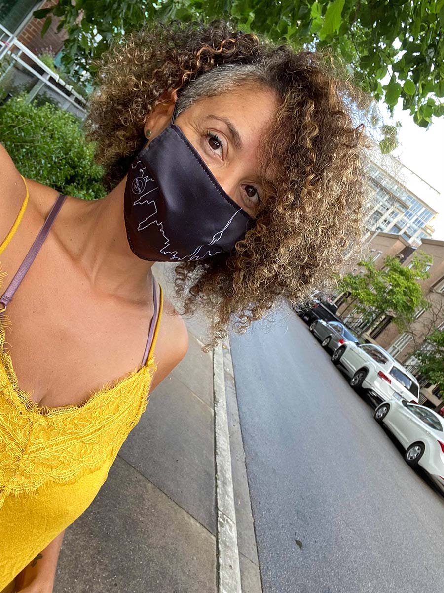 Nadia Lloyd wearing her black face mask with the Toronto skyline, taking a selfie
